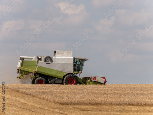 Combine harvesters on the field. Combine harvest on grain field. Summer harvest and blue sky. Harvesting on grain field. Harvests wheat in the fields in summer.