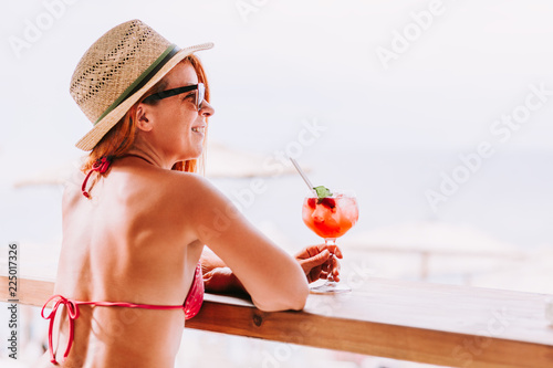Young woman enjoying cocktail in a beach bar