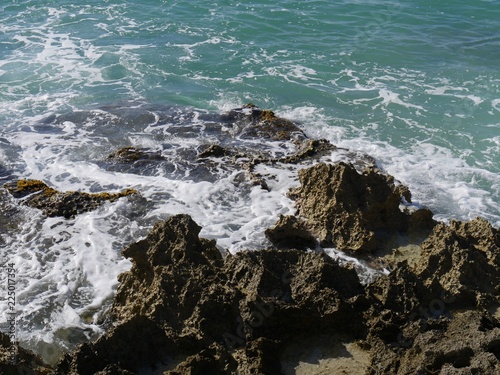 Top view of foaming waves breaking against sharp rocks at a tropical island