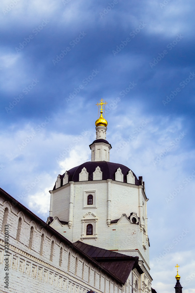 The dome of an Orthodox church with a gilded cross against a blue cloudy sky