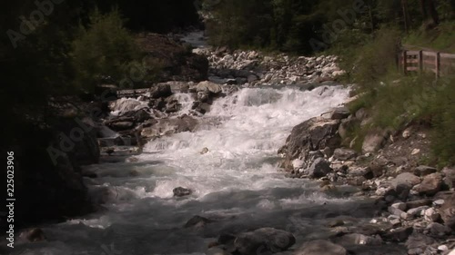 A small wild river flowing through the alpine valley Kalser Tal in Tirol, Austria. Zoom out from little waterfall to wide shot. photo