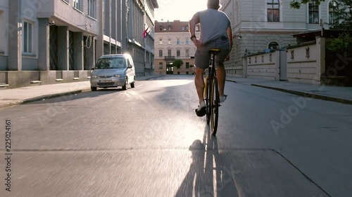 Behind young man swerving with his bicycle on the city street photo