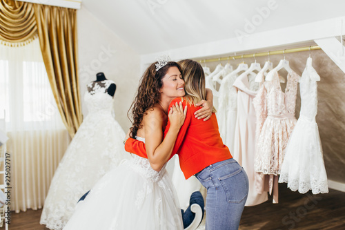 Beautiful young brunette woman choosing wedding dress in a bridal salon.