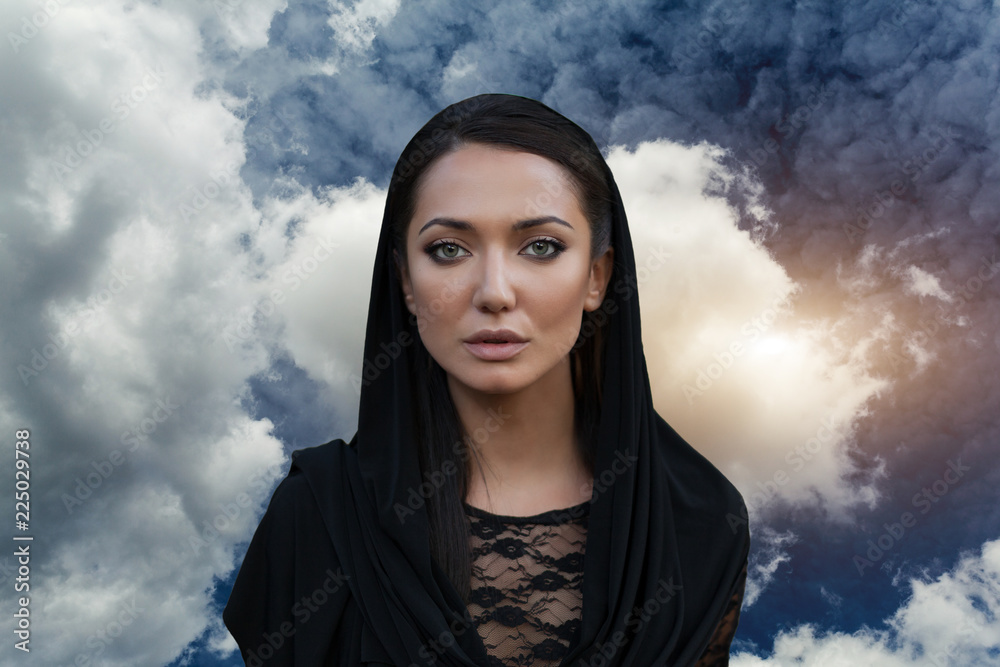 Φωτογραφία Young beautiful woman with a black hair and in the black dress with the sky back
