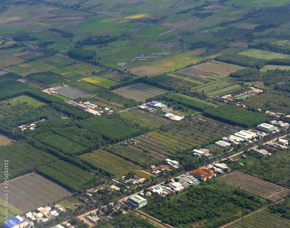 Medium wide aerial view of farms and structures seen while approaching Ho Chi Minh City in Vietnam.