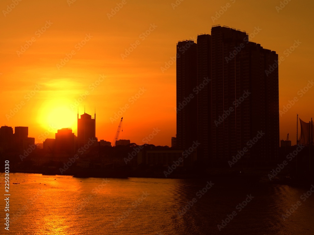 Skyline and buildings of Saigon silhouetted against a beautiful sunset in the Mekong River. Skyline and buildings of Saigon silhouetted against a beautiful sunset in the Mekong River.
