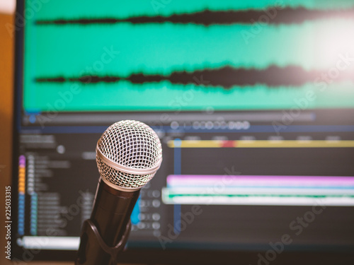 Microphone with computer screen in background with editing software. Home studio concept