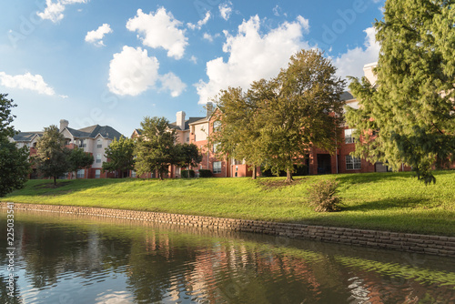 Typical multistory riverside apartment building complex surrounded by mature trees in Irving, Texas, USA.