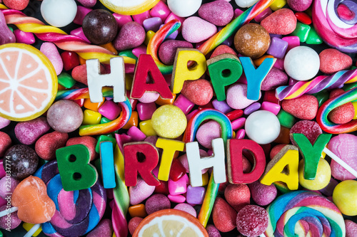 background from variety of sweet, lollipops, chewing gum, candies, marshmallows and the words birthday. congratulations for the holiday