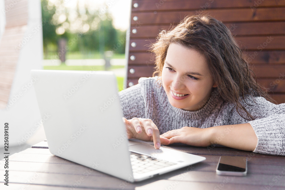 girl looking at laptop screen. Young woman with phone and notebook girl looking at laptop screen. Young woman with phone and notebook