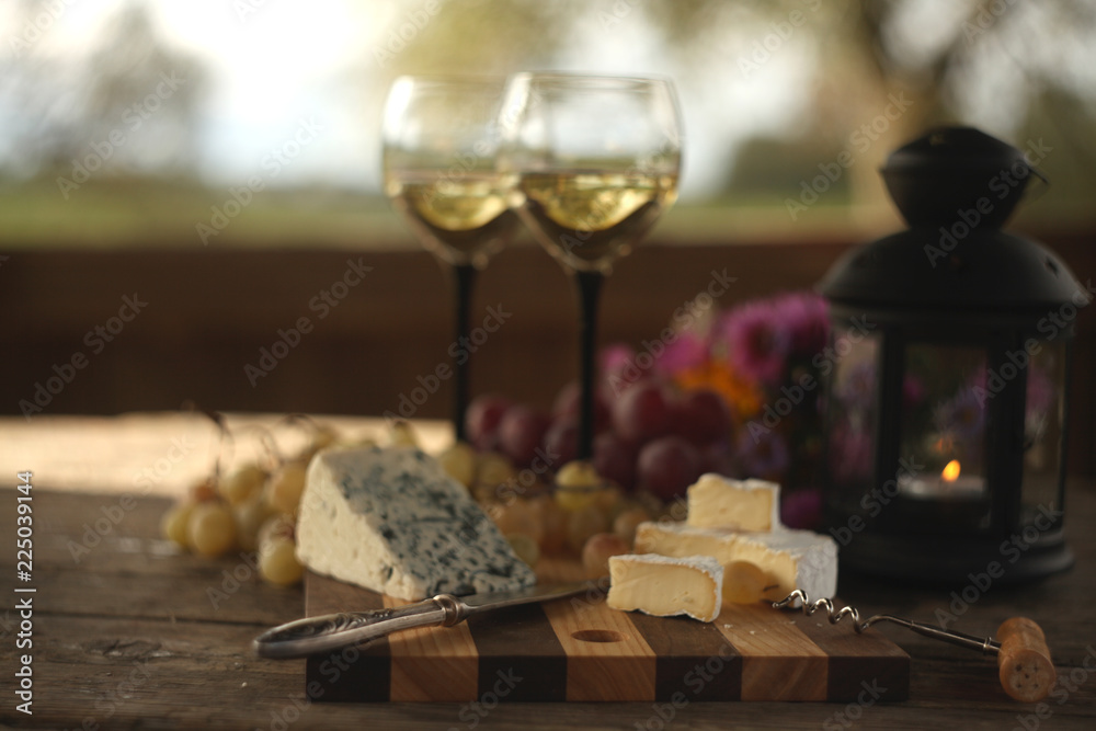 wine in a bottle,a glasses of white wine, grapes,various cheese and ,blue cheese,cheese Camembert, a bouquet and a lantern on the old table