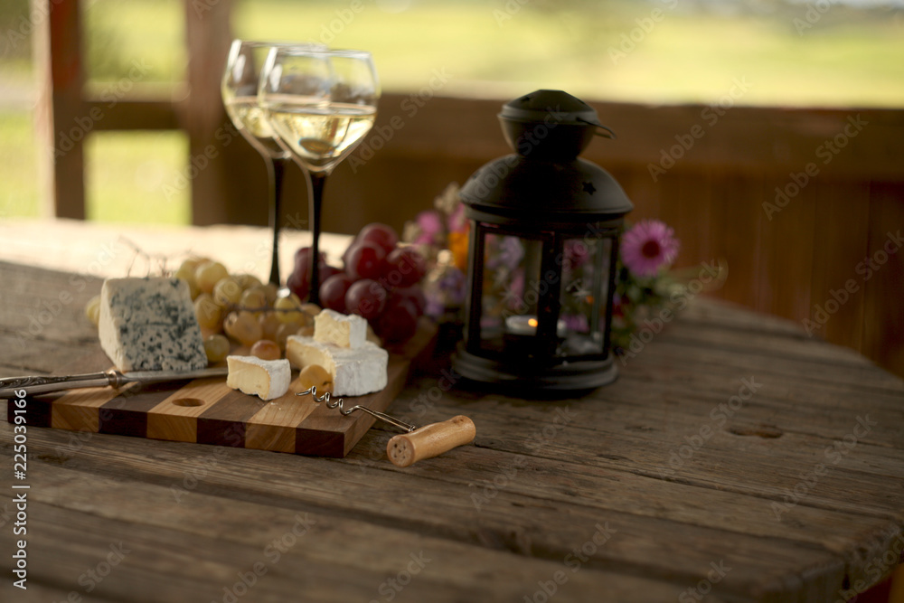 wine in a bottle,a glasses of white wine, grapes,various cheese and ,blue cheese,cheese Camembert, a bouquet and a lantern on the old table wine in a bottle,a glasses of white wine, grapes,various cheese and ,blue cheese,cheese Camembert, a bouquet and a lantern on the old table