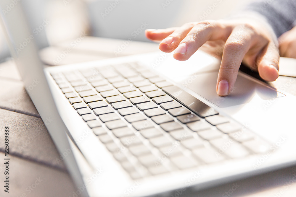 Hand clicking on laptop keyboard. Hand and notebook on table in the park Hand clicking on laptop keyboard. Hand and notebook on table in the park