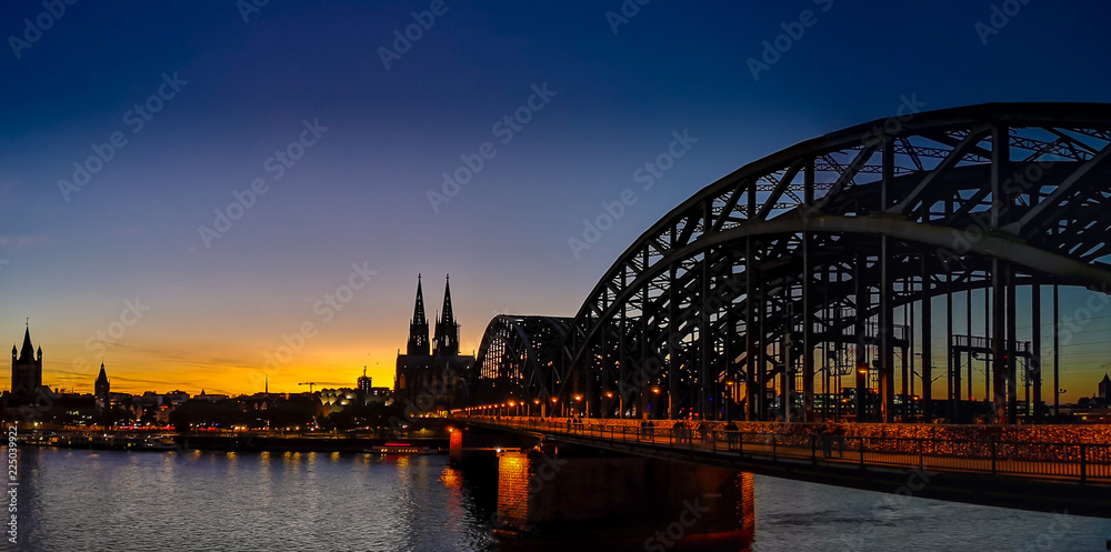 Kölner Dom mit Deutzer Brücke bei Sinnenuntergang bei wolkenlosem Himmel, sicht von der  Schäl Sick