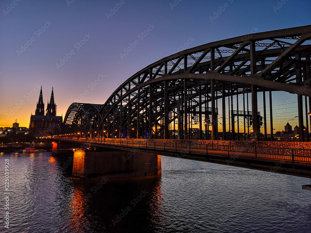 Naklejka premium Köln Stadtansicht Deztzer Brücke mit Kölner Dom und dem Rhein bei Abendstimmung mit warmen farben bei wolkenlosem Himmel