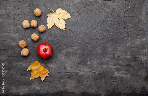 Red, ripe pomegranate, nuts and fallen yellow maple leaves. Fruits of autumn  photo