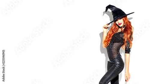 Halloween. Sexy witch with bright makeup and long red hair. Beautiful young woman posing in witches sexy costume over white background