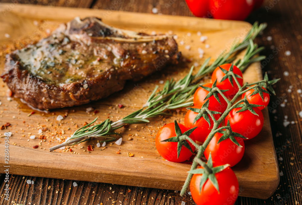 Grilled steak on the bone and tomatoes on a branch Grilled steak on the bone and tomatoes on a branch