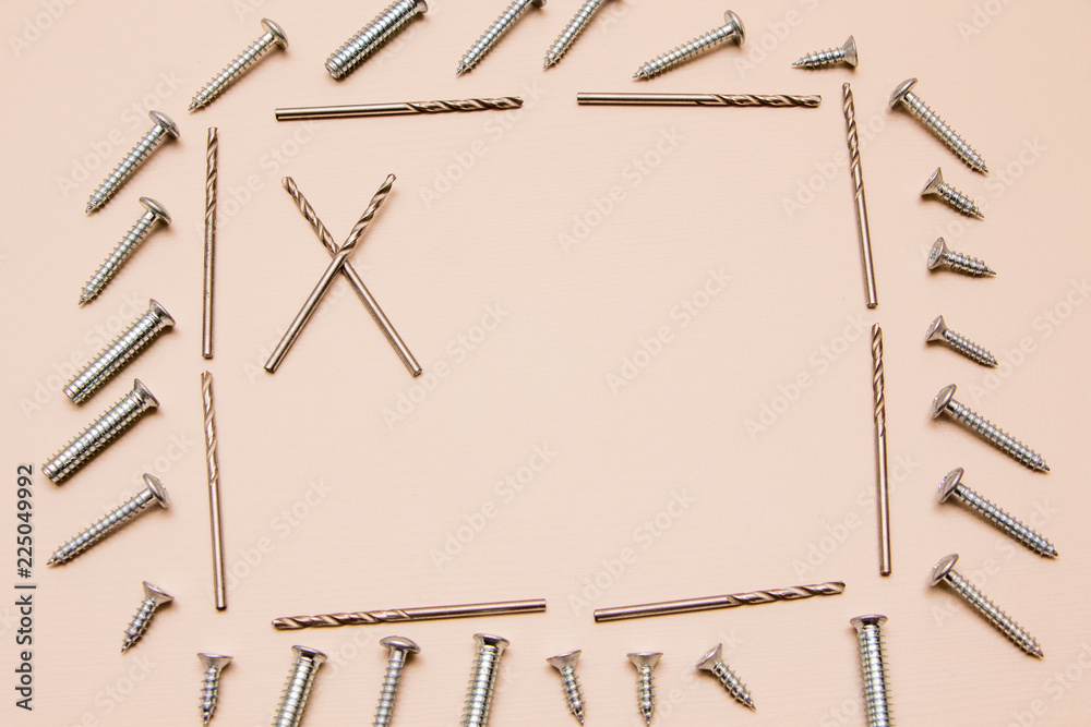 Drill bit and self-tapping screw on a wooden background shaped like a frame. Drill bit and self-tapping screw on a wooden background shaped like a frame.