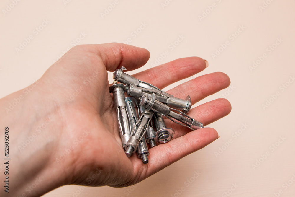 Wall plug or anchor or rawlplug in the hand on a wooden background Wall plug or anchor or rawlplug in the hand on a wooden background