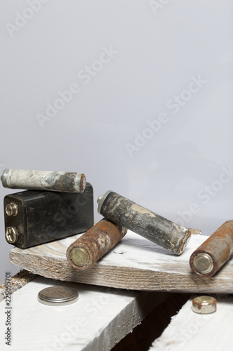 Used finger-wound batteries covered with corrosion. They lie on a wooden box. Recycling.