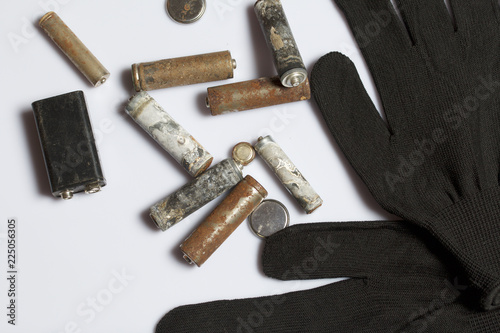 Used finger-wound batteries covered with corrosion. Next working gloves. Recycling.