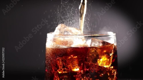 Cola with Ice and bubbles in glass slow motion. photo