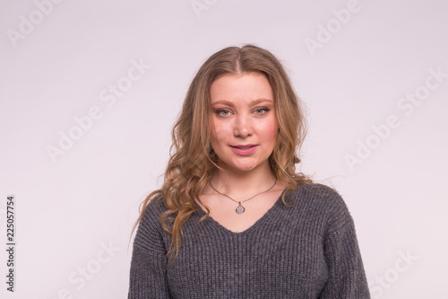 Young blonde woman wearing grey wool sweater on white background
