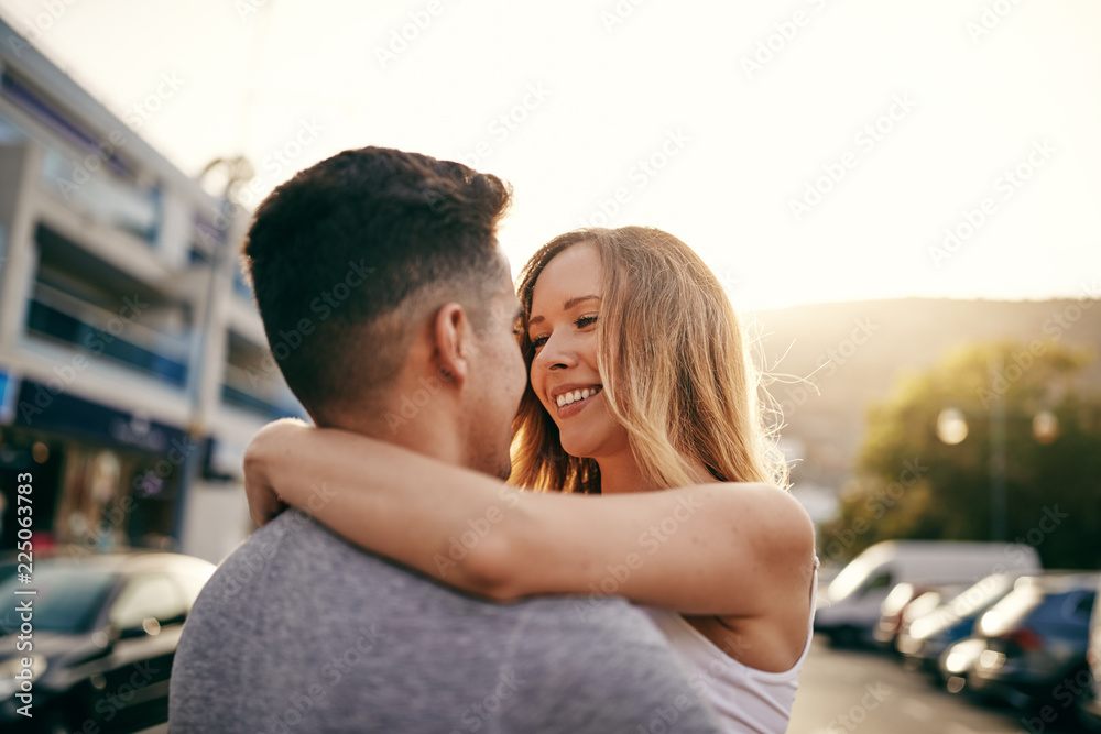 Loving couple embracing on a city street at sunset