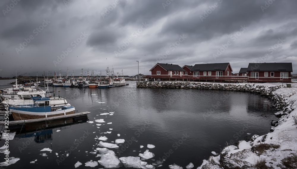 Scenic view of beautiful winter sea coast with fisherman boats and red rorbu houses at Lofoten Islands in Northern Norway