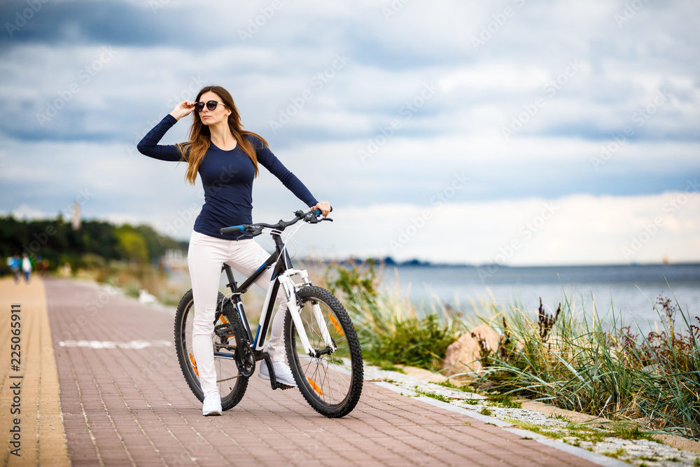 Young woman and bike at seaside Young woman and bike at seaside