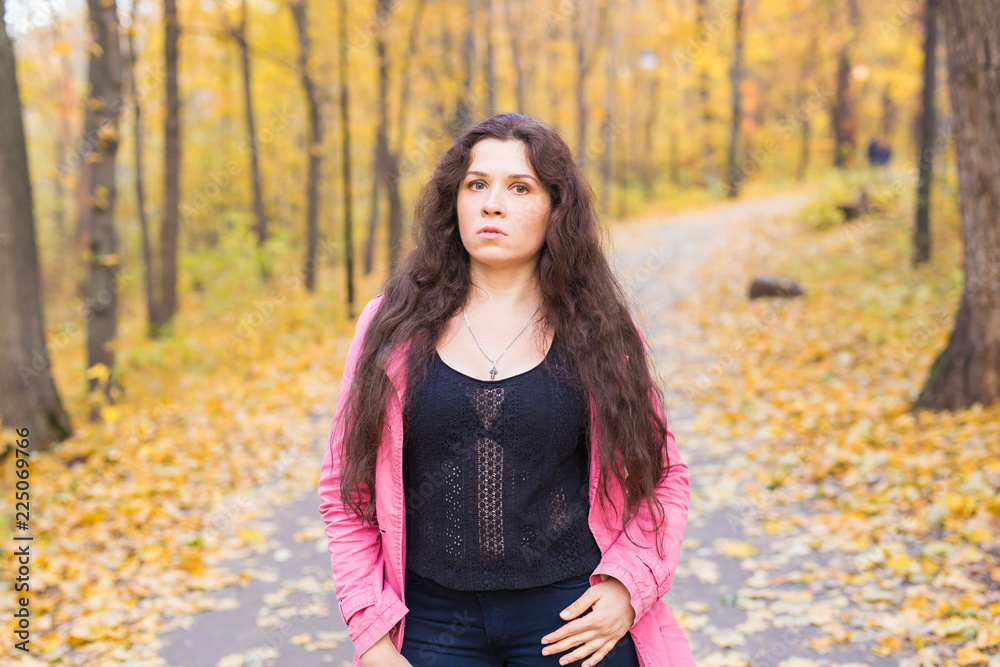 Portrait of a beautiful and dreamy young woman with long wavy hair in autumn park Portrait of a beautiful and dreamy young woman with long wavy hair in autumn park