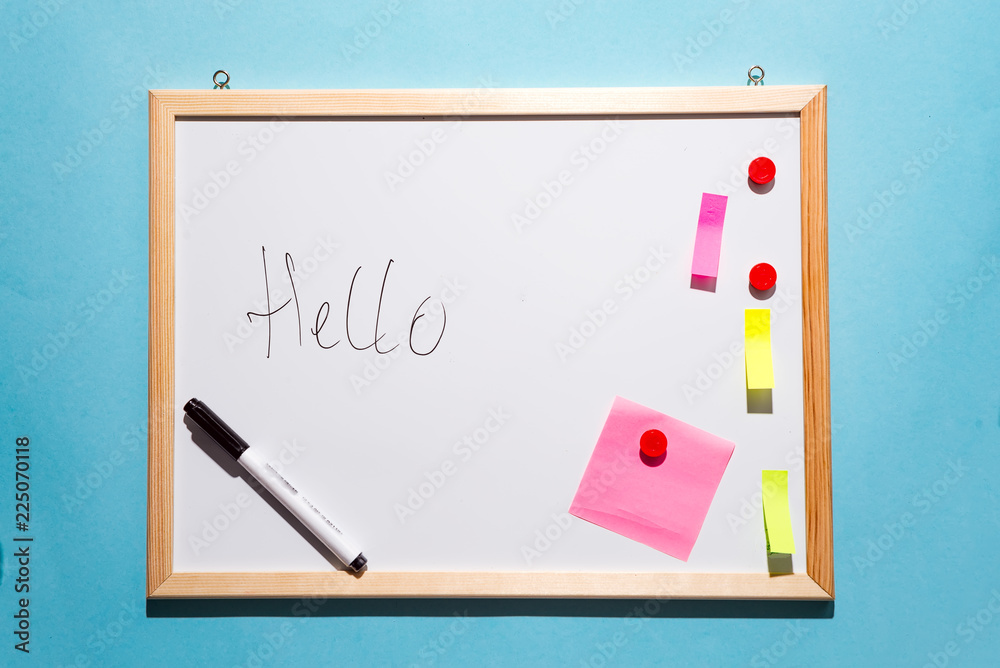 White board with marker pen and scratch paper isolated on blue paper background, top view with copy space