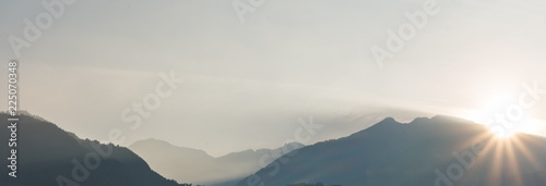 panorama view of a mountain landscape in silhouette with the sun setting