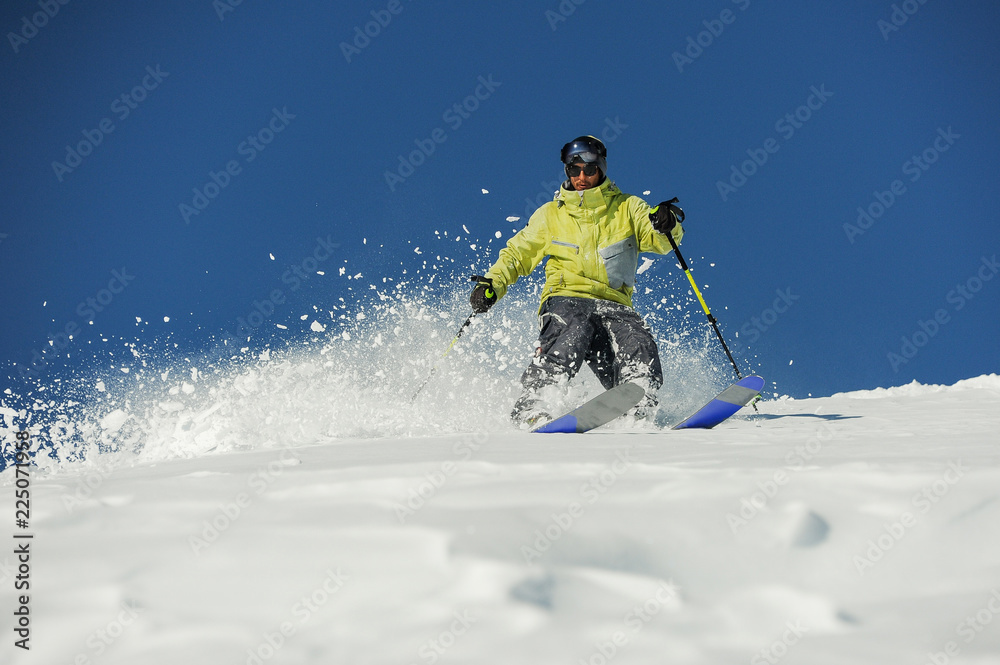 Young skier in yellow sportswear riding down the slope in Georgia, Gudauri