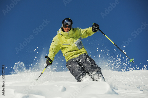 Happy skier in yellow sportswear riding down the slope in Georgia, Gudauri