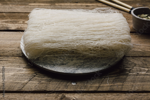 Uncooked rice noodles, on rustic wooden table photo