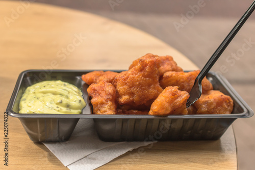 Fried pieces of fish, called kibbeling, with tasty remoulade sauce in a black plastic box with a plastic fork. Typical and very delicious dutch fast food, served as a meal in the netherlands.