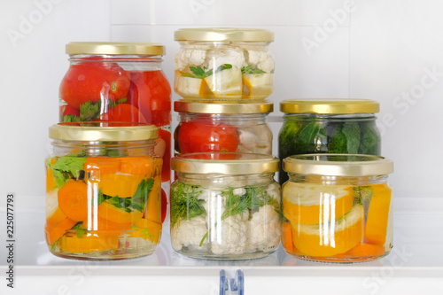 Variety glass jars homemade pickled vegetables stand in fridge. Fermented healthy natural vegetarian food concept.