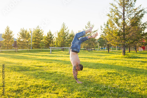 Yoga, fitness and healthy lifestyle concept - man doing a handstand on summer nature