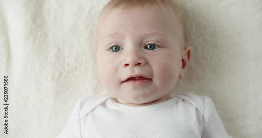 Cute caucasian baby lying on white bed sheet, happily smiling and laughing. happy childhood concept closeup 4k Cute caucasian baby lying on white bed sheet, happily smiling and laughing. happy childhood concept closeup 4k