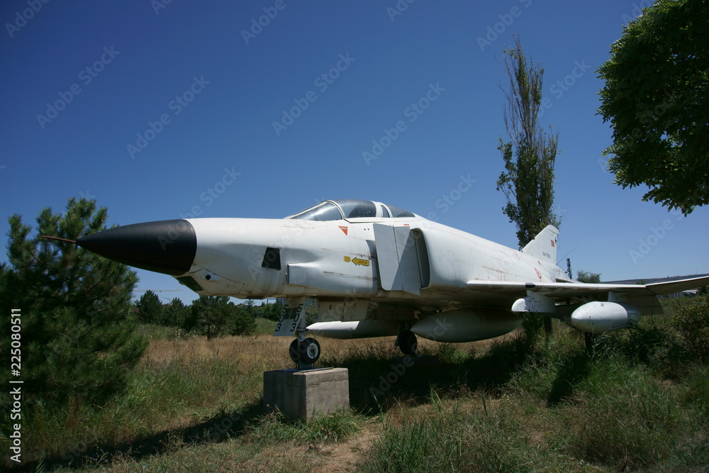 A fighter plane placed on a display stand on a grassy land A fighter plane placed on a display stand on a grassy land