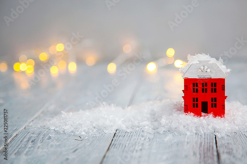 Bild auf Leinwand wooden toy house in a snow and light boche on a wooden background