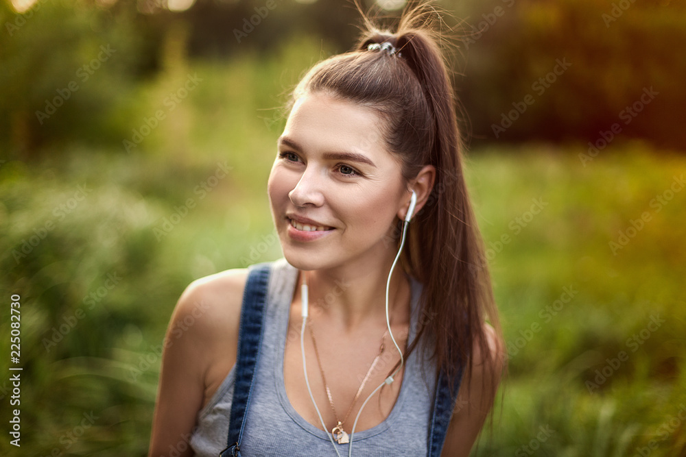 Portrait of a girl in headphones. Sport and healthy lifestyle, jogging on the street. Long and healthy hair. Portrait of a girl in headphones. Sport and healthy lifestyle, jogging on the street. Long and healthy hair.