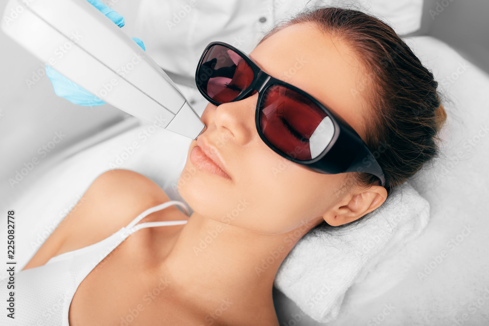 Beautiful woman having her facial hair removed by female beautician