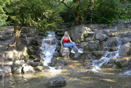junge Frau sitzt am Wasserfall