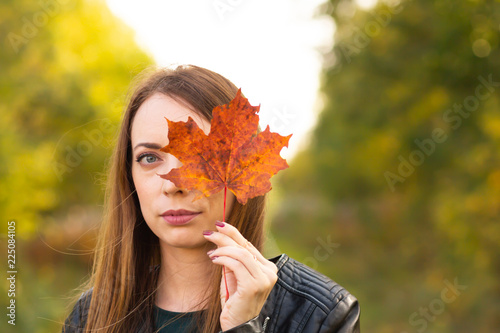 Pretty woman with autumn yellow maple leaves on forest background