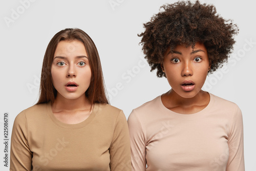 Quadro em tela Horizontal shot of diverse women gaze at camera with surprised expressions, stan