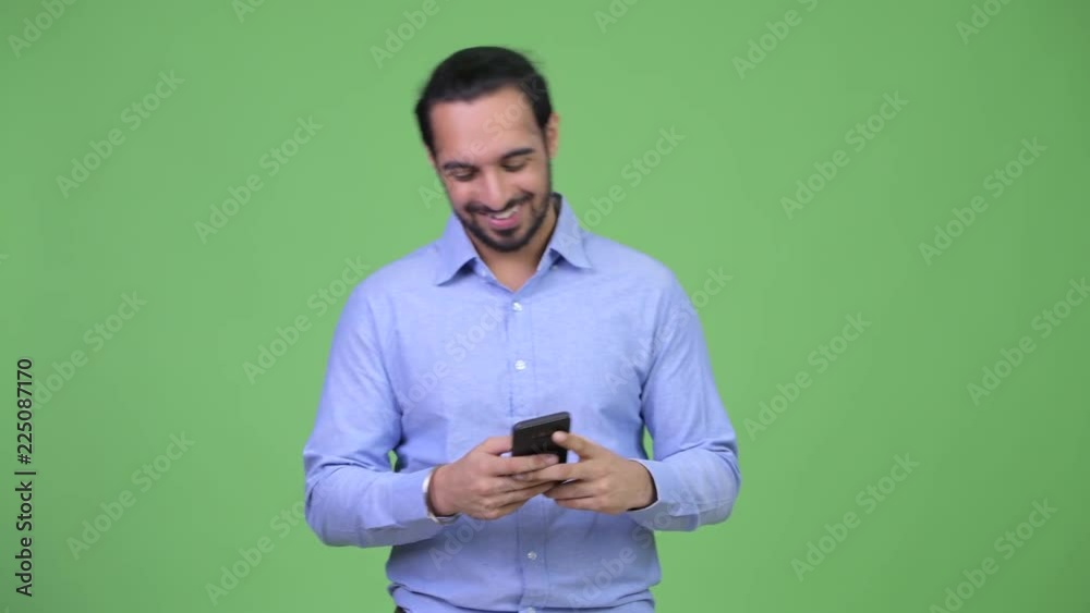 Young happy bearded Indian businessman using phone Young happy bearded Indian businessman using phone