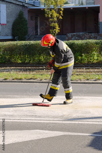 Straż pożarna. Strażak na służbie sprząta po zdarzeniu drogowym.